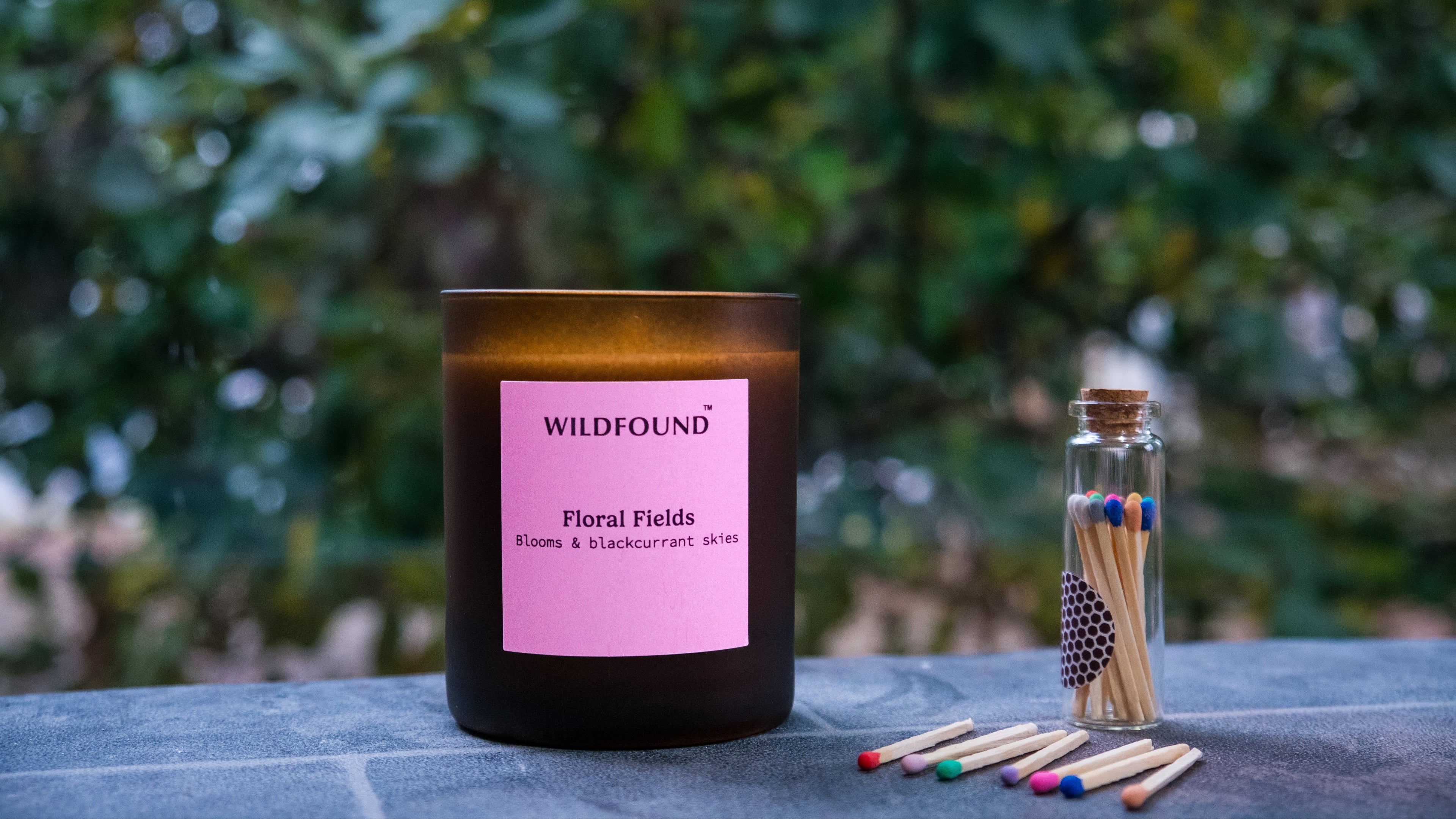 Canlde with colourful matches and greenery woodland in the background