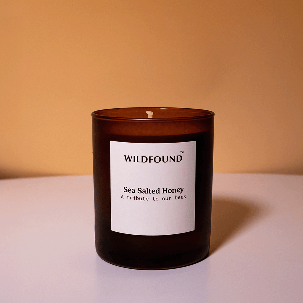Dark ember candle with a white label on a beige background