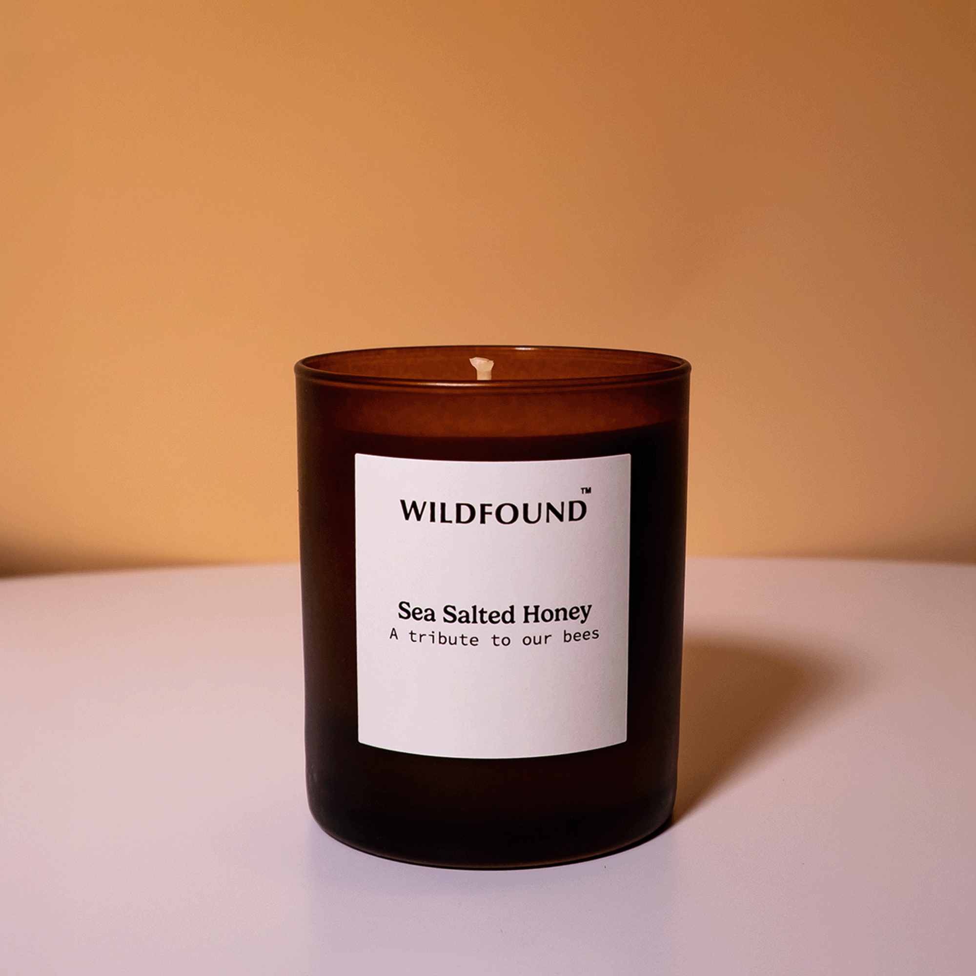Dark ember candle with a white label on a beige background