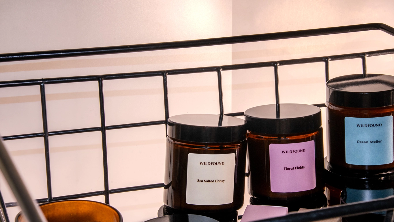 Three soy candles candles with labels on a black metal shelf.